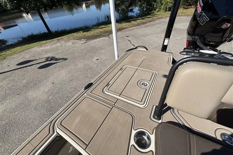 Slide: The Image of 2025 Mako 18 Pro Skiff Backwater Edition boat deck with seating and motor, near a lake. - 28