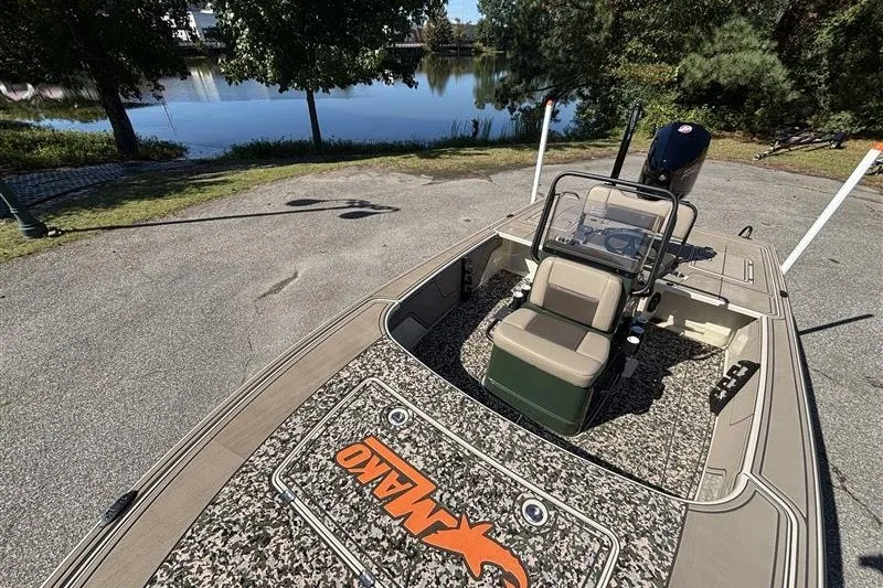 Slide: The Image of 2025 Mako 18 Pro Skiff Backwater Edition boat near a serene lake. - 18