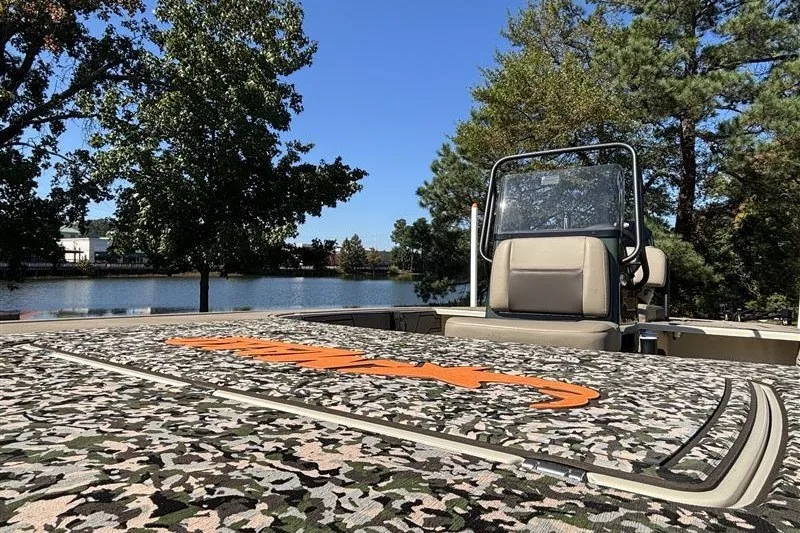 Slide: The Image of 2025 Mako 18 Pro Skiff Backwater Edition boat with camo design by a lake. - 16