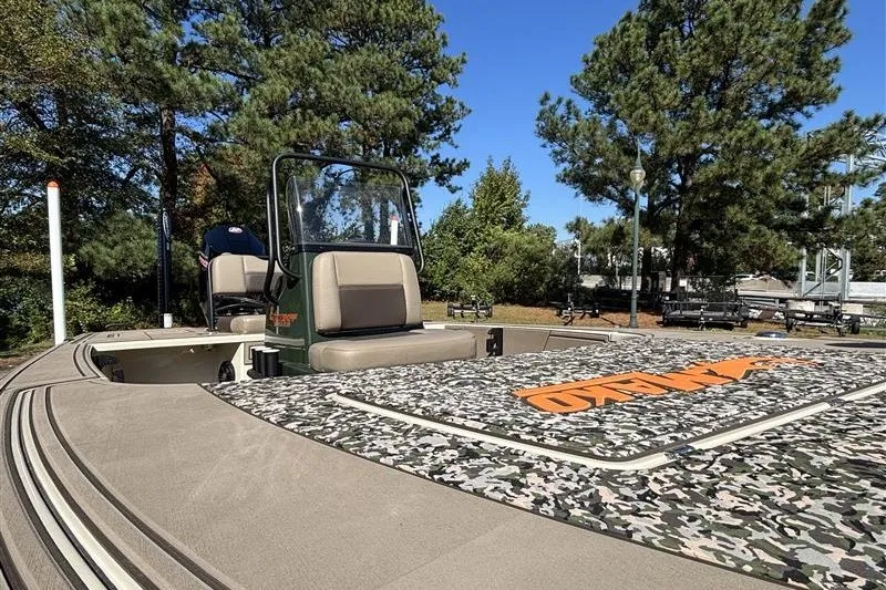 Slide: The Image of 2025 Mako 18 Pro Skiff Backwater Edition boat with camo deck, parked outdoors. - 17