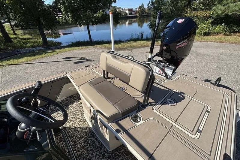 Slide: The Image of 2025 Mako 18 Pro Skiff Backwater Edition boat with seating and motor by a lake. - 25