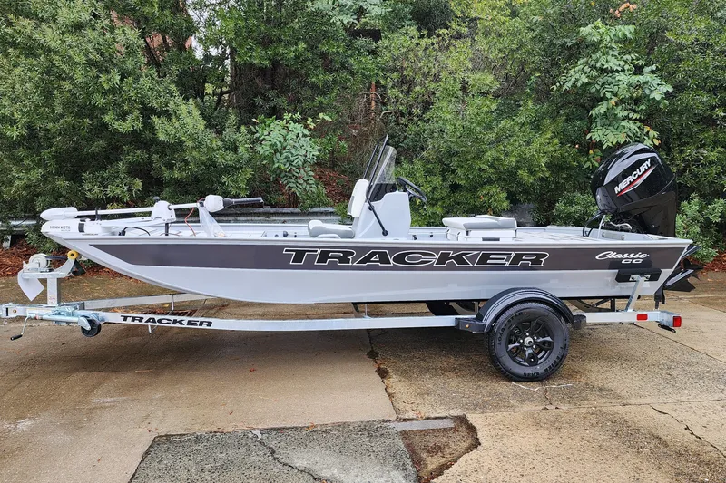 Slide: The Image of 2027 Tracker Bass Tracker Classic CC boat on trailer, surrounded by greenery. - 59