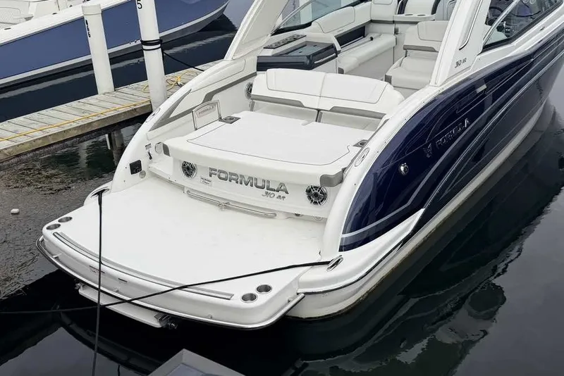 Slide: The Image of 2023 Formula 310 Bowrider I/O boat docked, showcasing sleek design and spacious seating. - 2