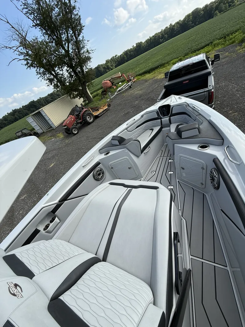 Slide: The Image of The image shows the interior of a 2024 Sunsation 32 CCX boat with sleek white seating and gray accents. A tractor and trailer are visible in the background. - 4