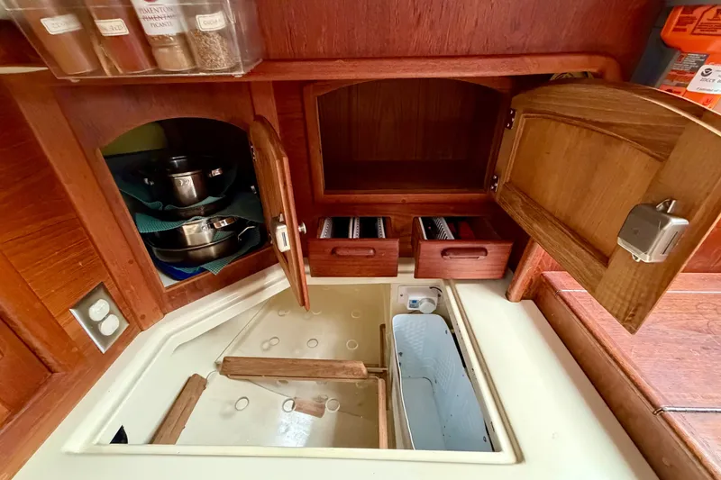 Slide: The Image of Galley storage in 1997 Pacific Seacraft Crealock 37 sailboat with open cabinets and drawers. - 28