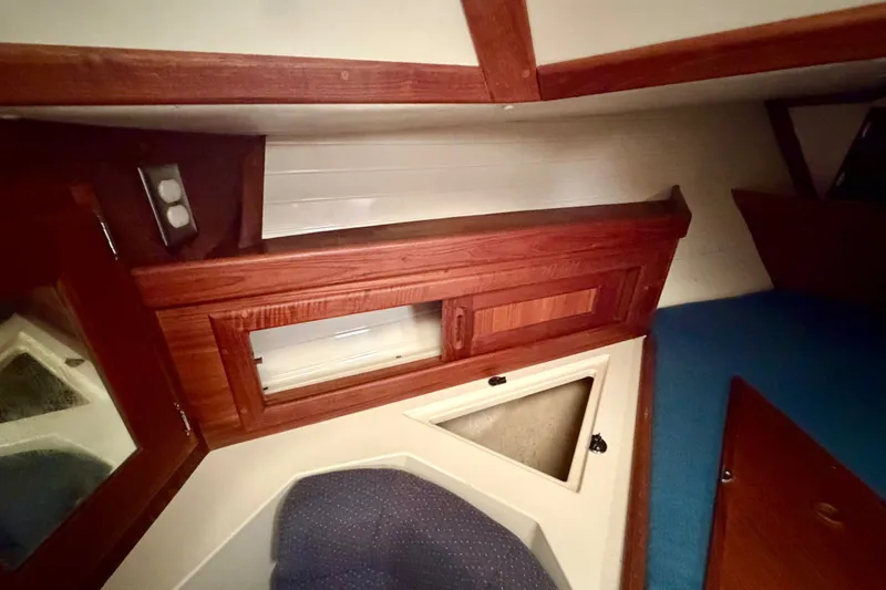 Slide: The Image of Interior of 1997 Pacific Seacraft Crealock 37 sailboat, featuring wooden cabinetry and blue upholstery. - 73