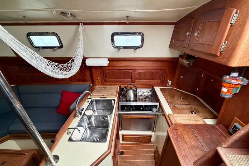 Slide: The Image of Interior of 1997 Pacific Seacraft Crealock 37 sailboat, featuring a cozy kitchen and seating area. - 24
