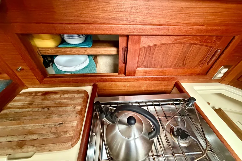 Slide: The Image of Galley kitchen of 1997 Pacific Seacraft Crealock 37 with wooden cabinets and stainless steel stove. - 31