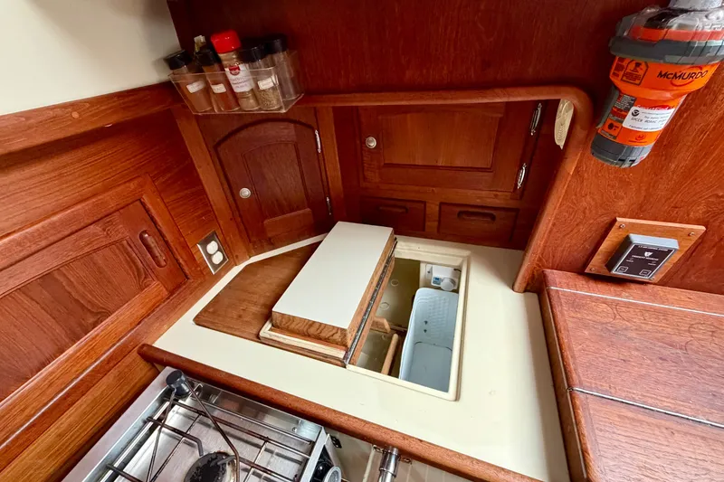 Slide: The Image of 1997 Pacific Seacraft Crealock 37 yacht galley with wooden cabinetry and spice rack. - 25