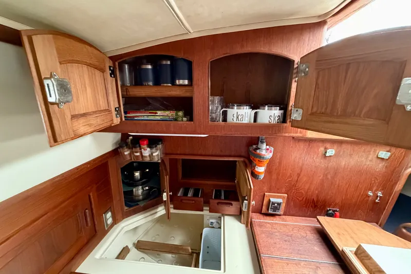 Slide: The Image of Cozy 1997 Pacific Seacraft Crealock 37 yacht kitchen with wooden cabinets and organized storage. - 29