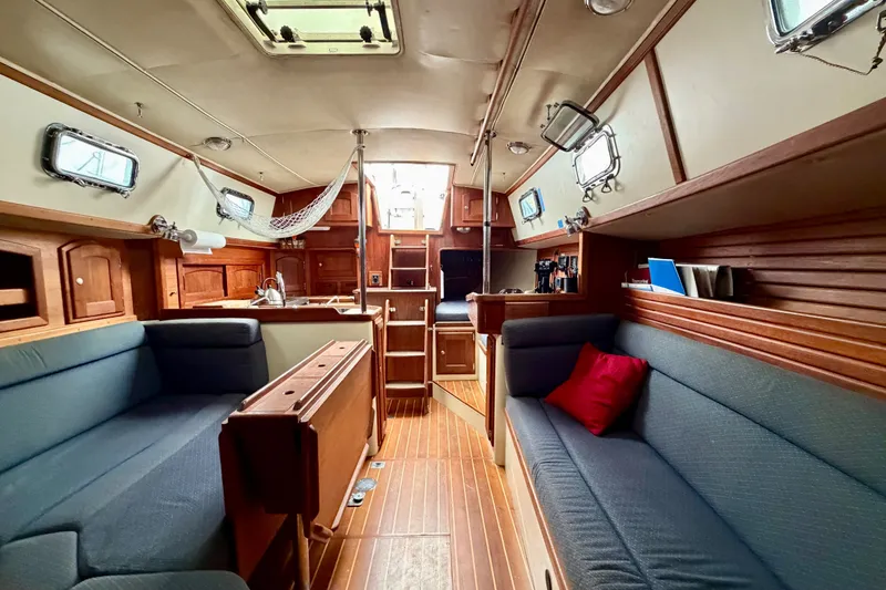 Slide: The Image of Interior of 1997 Pacific Seacraft Crealock 37 sailboat, featuring cozy seating and wooden cabinetry. - 80