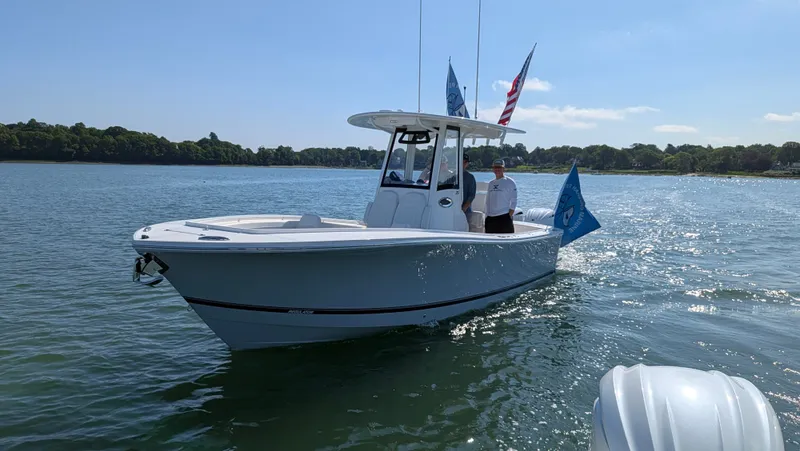 Slide: The Image of A 2025 Regulator 25 boat on calm water with flags and two people on board. - 3