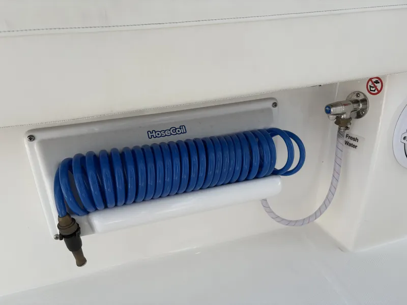 Slide: The Image of A blue hose is neatly coiled and mounted on a white wall. - 23