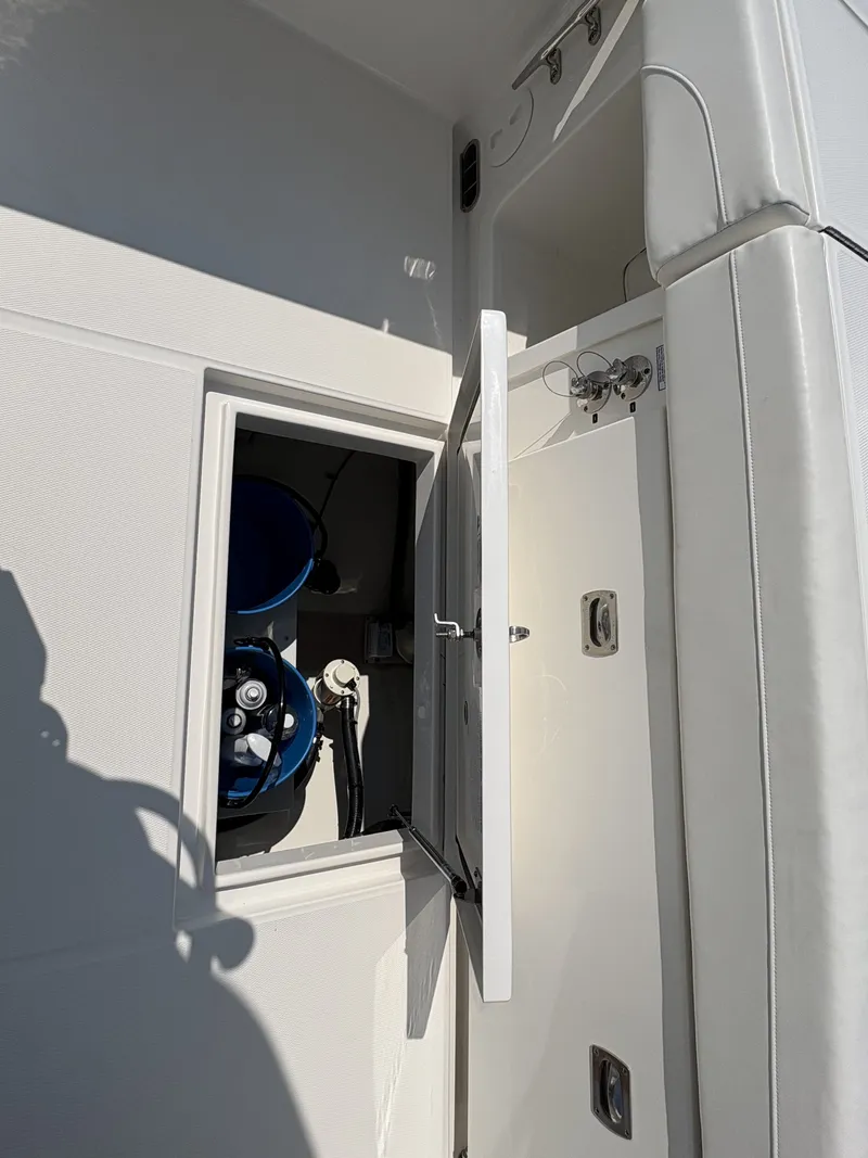 Slide: The Image of An open storage compartment on a boat with visible blue tanks and hoses. - 49
