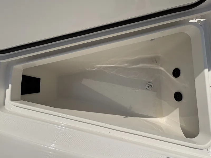 Slide: The Image of An open storage compartment on a 2025 Regulator 25 boat, featuring a drain and smooth white walls. - 41