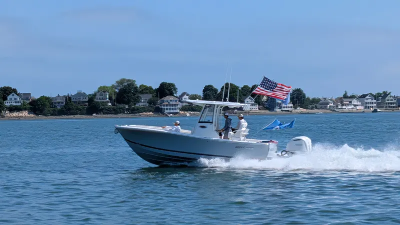 The Image of A 2025 Regulator 25 boat cruising on the water, with an American flag waving in the wind. - 1