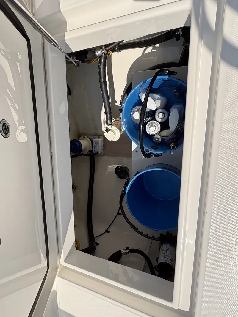Slide: The Image of An open storage compartment with blue buckets and hoses inside a boat. - 48