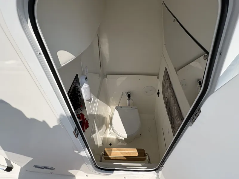 Slide: The Image of The image shows a clean, modern boat toilet with white walls and a wooden floor. - 33