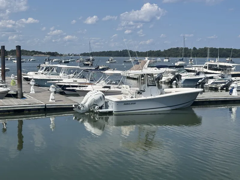 Slide: The Image of A 2025 Regulator 25 boat docked in a sunny marina, surrounded by other boats. - 8