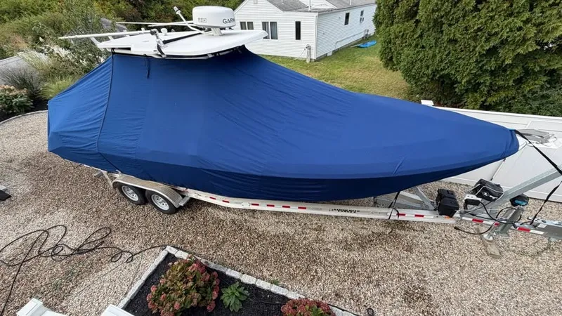 Slide: The Image of A 2007 Everglades 290 CC boat is covered on a trailer. It is parked in a yard. - 17