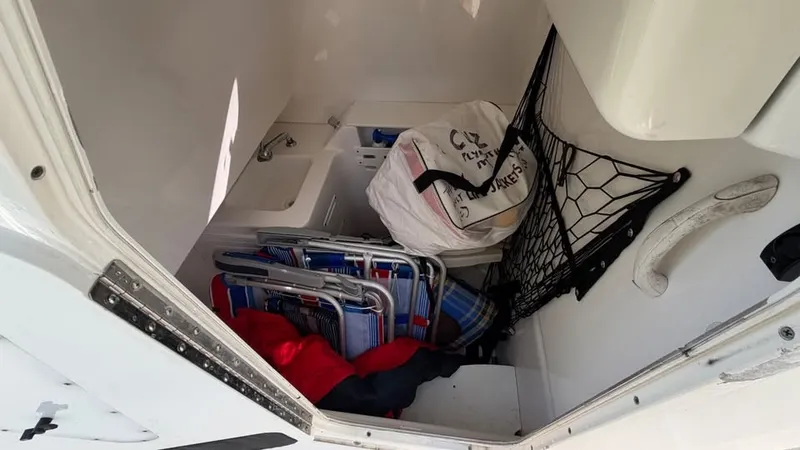 Slide: The Image of The storage area of a 2007 Everglades 290 CC boat contains folding chairs and a bag. - 15
