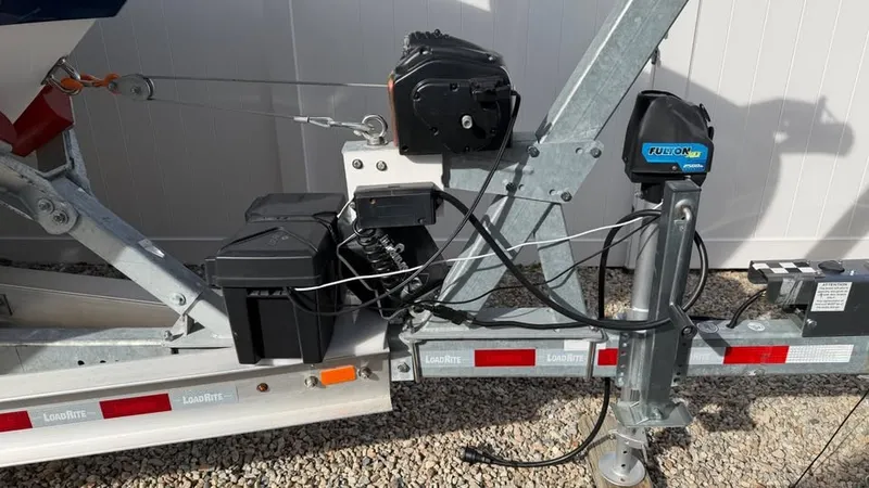 Slide: The Image of A boat trailer with electrical components and cables, parked on a gravel surface. - 19