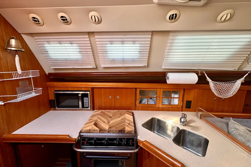 Slide: The Image of Interior of 2007 Hunter 41 Deck Salon yacht kitchen with microwave, sink, and wooden cabinetry. - 10