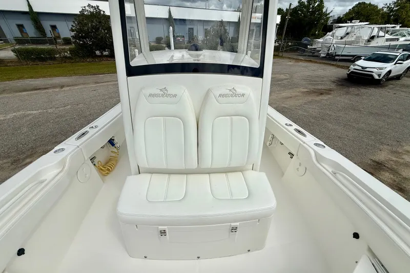 Slide: The Image of 2021 Regulator 24XO boat with white seating and console, parked outdoors. - 13