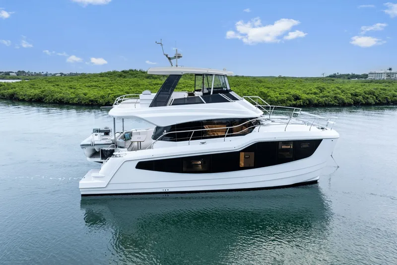 Slide: The Image of 2027 Aquila 50 on calm water with lush greenery in the background. - 24