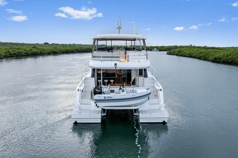 Slide: The Image of A luxurious 2027 Aquila 50 yacht cruising on a calm river with lush greenery along the banks. - 22