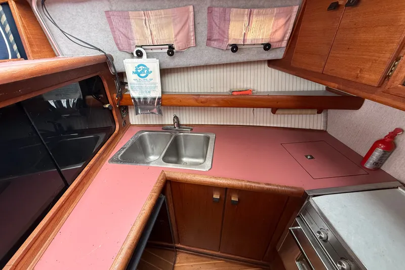 Slide: The Image of 1987 Bayliner 3270 Motoryacht kitchen with dual sink, pink countertop, and wooden cabinets. - 24