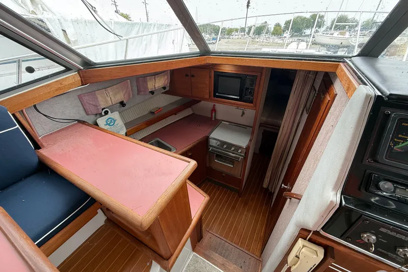 Slide: The Image of 1987 Bayliner 3270 Motoryacht interior with wood accents, kitchenette, and seating area. - 23