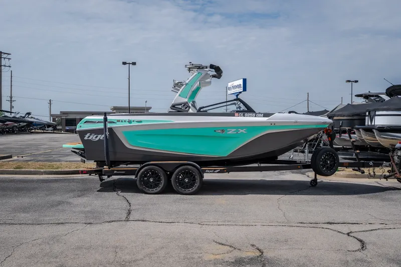 Slide: The Image of 2021 Tigé 21ZX boat on trailer, teal and gray design, parked outdoors. - 49