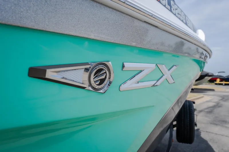 Slide: The Image of 2021 Tigé 21ZX boat, turquoise hull with ZX emblem, parked on a trailer. - 4