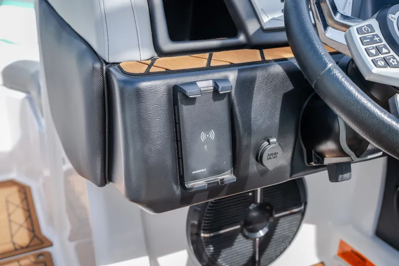 Slide: The Image of Dashboard of 2021 Tigé 21ZX boat featuring wireless charging pad and steering wheel controls. - 21