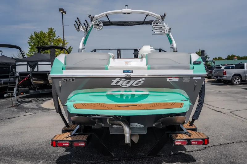 Slide: The Image of 2021 Tigé 21ZX boat, rear view, showcasing sleek design and vibrant colors in a parking lot. - 2