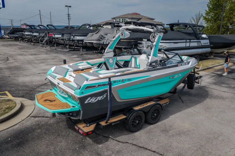 Slide: The Image of 2021 Tigé 21ZX boat in a parking lot, showcasing sleek design and vibrant turquoise color. - 42