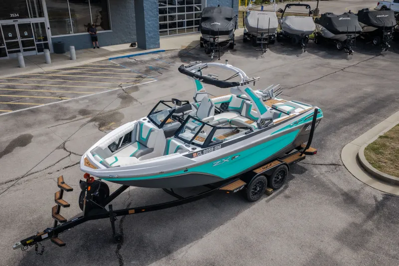 Slide: The Image of 2021 Tigé 21ZX boat on trailer in parking lot, teal and white design. - 46