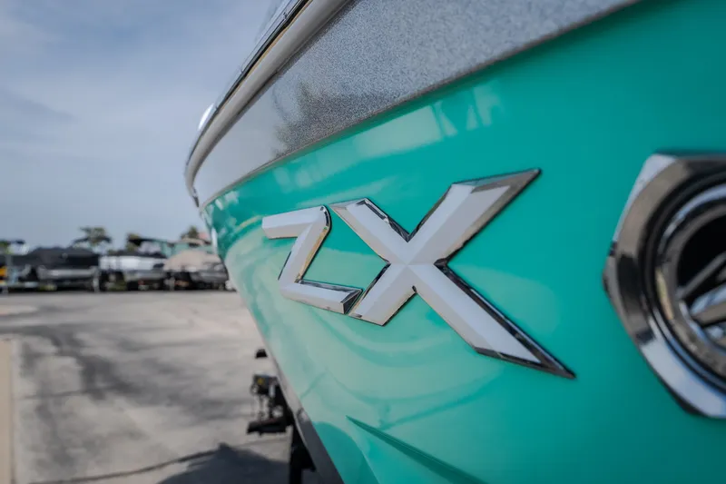 Slide: The Image of Close-up of 2021 Tigé 21ZX boat with turquoise hull and chrome ZX emblem. - 11