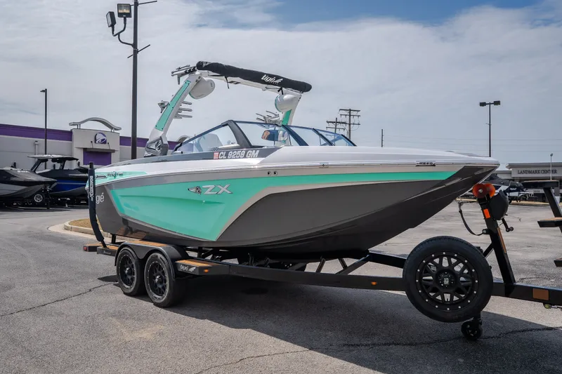 Slide: The Image of 2021 Tigé 21ZX boat on trailer, displayed outdoors at a dealership. - 50