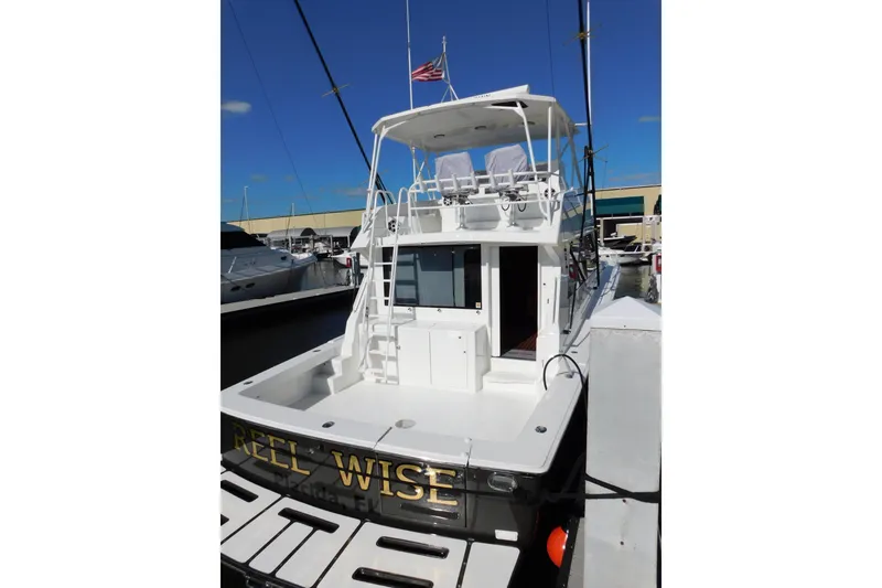 Slide: The Image of 1996 Viking 50 Convertible yacht docked, featuring spacious deck and flybridge under clear blue sky. - 4