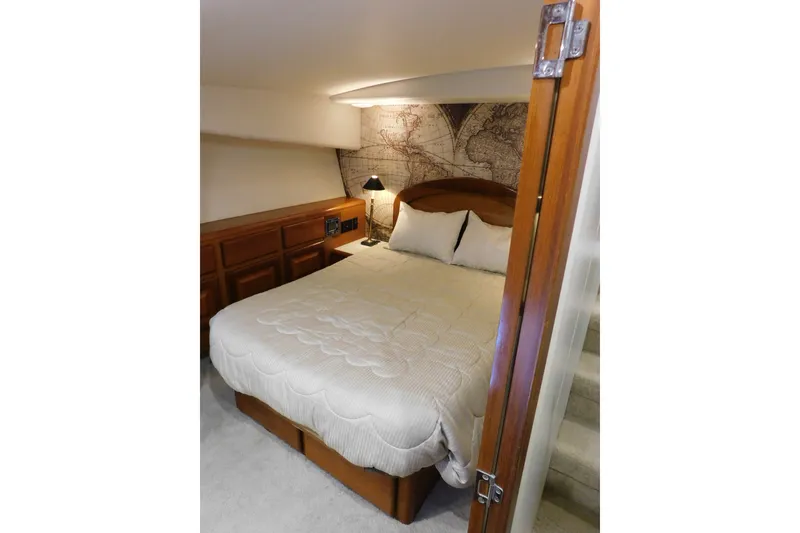 Slide: The Image of Cozy master berth in 1996 Viking 50 Convertible yacht with map-themed decor and wooden accents. - 51