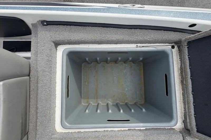 Slide: The Image of 2024 Nitro Z20 boat storage compartment, open and empty, with gray interior and carpeted edges. - 69