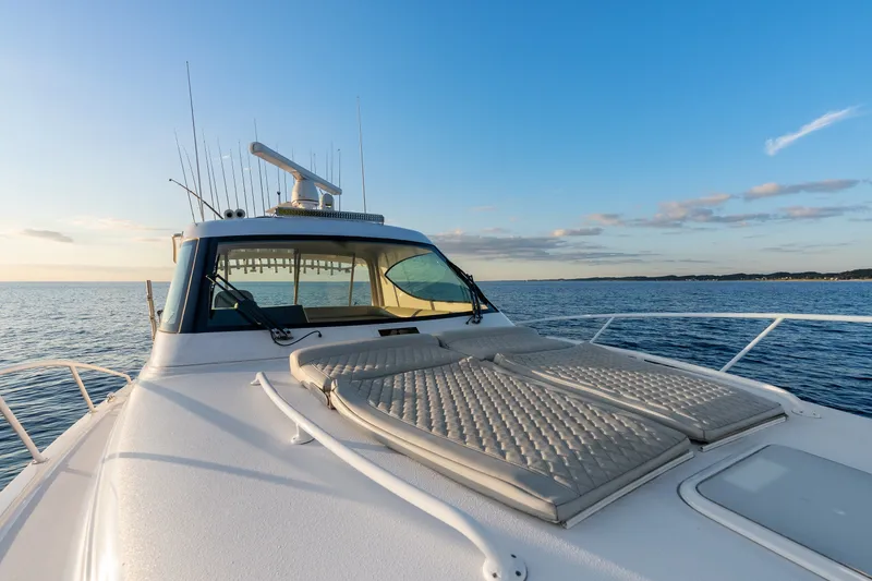 Slide: The Image of 2021 Jupiter 41 SB yacht on open sea at sunset, featuring sun pads and fishing rods. - 22