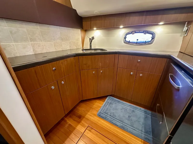 Slide: The Image of 2018 Tiara Yachts 4300 Open galley with wood cabinets and stainless steel sink. - 26