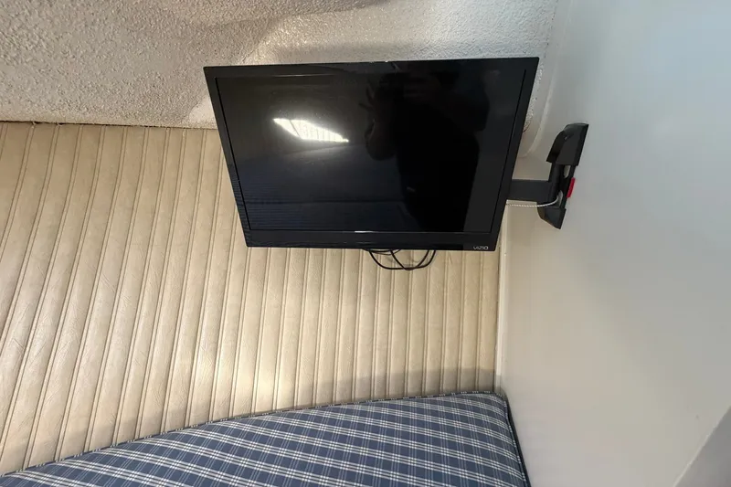 Slide: The Image of Mounted TV inside 1973 Chris-Craft 31 Sedan Cruiser with striped upholstery and plaid cushion. - 54