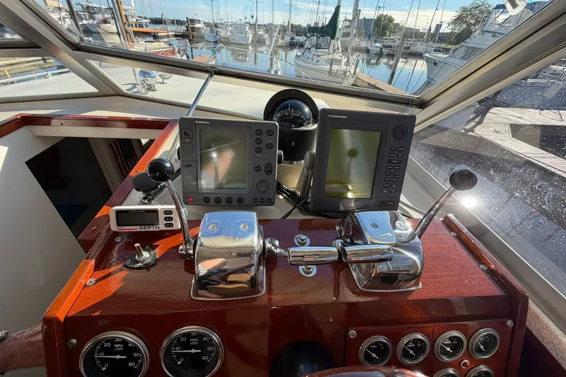 Slide: The Image of 1973 Chris-Craft 31 Sedan Cruiser helm with navigation instruments and marina view. - 41