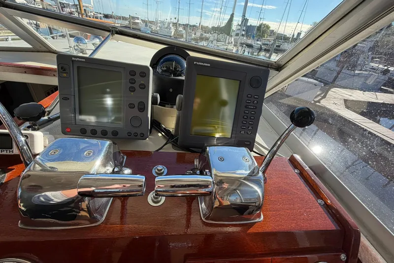 Slide: The Image of 1973 Chris-Craft 31 Sedan Cruiser helm with navigation equipment and controls in a marina setting. - 40