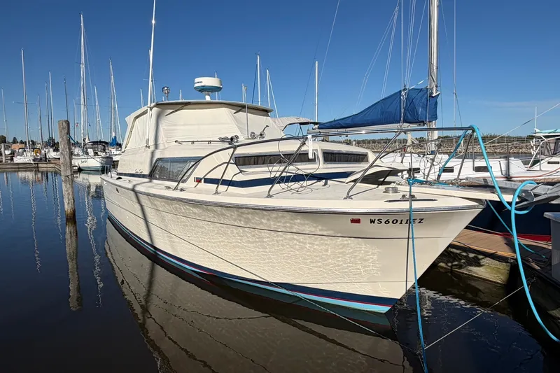 Slide: The Image of 1973 Chris-Craft 31 Sedan Cruiser docked in a marina under clear blue skies. - 7