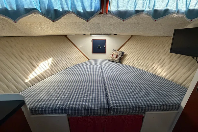 Slide: The Image of Cozy cabin interior of 1973 Chris-Craft 31 Sedan Cruiser with nautical decor and checkered bedding. - 52